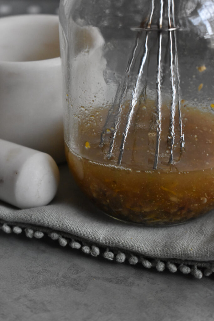 Jar of herbal bitters with a whisk.